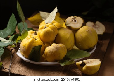 Ripe yellow quince fruits on a plate on a wooden table. Photo in a low key in a rustic style - Powered by Shutterstock