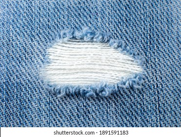 Ripped Blue Hipster Jeans Material. Destroyed Denim Cloth Texture. Close Up.