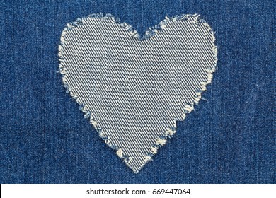 Ripped denim heart frame on denim jeans background. Denim jeans fashion background.
