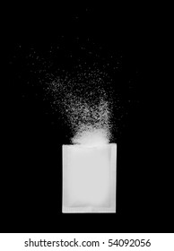 A Ripped Open Sugar Packet With Sugar Crystals Spilling Out, Isolated On Black Background