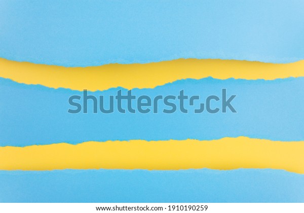 Ripped paper edge with copy space, blue\
and yellow color background. Flat lay. Copy\
space.