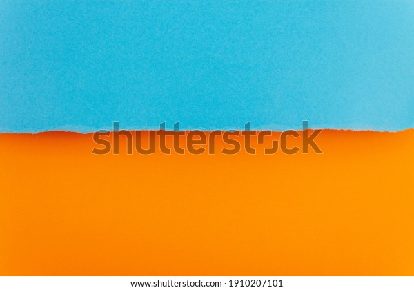 Ripped paper edge with copy space, blue\
and orange color background. Flat lay. Copy\
space.