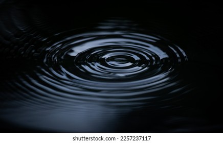 Ripple of water or water drop splash on black background. Abstract shape out of the water - Shutterstock ID 2257237117