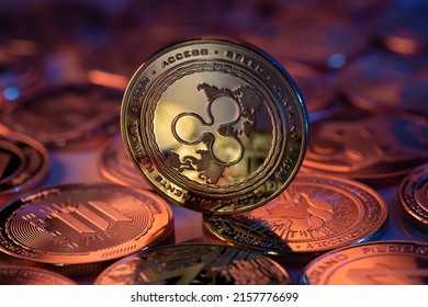 Ripple XRP Cryptocurrency Physical Coin placed on crypto altcoins and lit with orange and blue lights in the dark Backgrond. Macro shot. Selective focus. - Shutterstock ID 2157776699