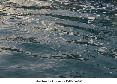 Ripples And Foam From A Motor Boat Wake In Blue Green Sea Water