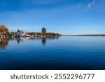 Rippling water leading up to waterfront autumn treelined shore of Brockville on the St. Lawrence River under a blue sky