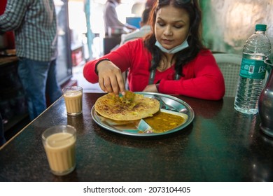 Rishikesh, Uttarakhand, India-Nov 7 2021: A Tourist Woman Eating Aloo Paratha And Tea At Small Restaurant In Rishikesh City.