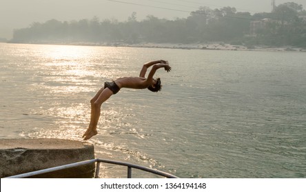 Rishikesh, Uttrakhand / India - 26 April, 2016 - An Unidentified Boy Is Doing A Backflip Into River Ganges. It's A Daring Act As The Water Is Chilled And Flowing Fast.