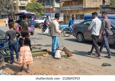 Rishra, 02-13-2022: People Walking In Street Looking At A Street Performer Waiting With His Pet Monkey. It Is A Vintage Profession Where Trained Monkeys Entertain The Crowd And Earn For His Trainer.