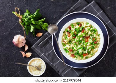 Risi e Bisi, Venetian Risotto with Spring Peas and chunks of ham in a bowl on a concrete table with ingredients, italian cuisine, horizontal view from above, flat lay, free space