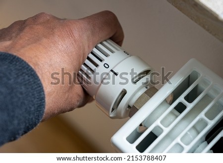 Rising heating costs in the crisis: Man regulates the temperature at home with the heating thermostat to save energy, close up with hand Foto stock © 