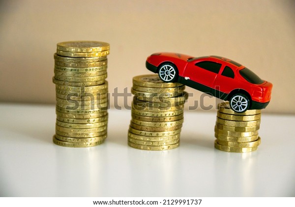 Rising and increasing cost of fuel, price of running a\
car concept background. Idea for saving for a first car. More\
expensive petrol, diesel, gasoline, driving concepts with British\
coins. Blur 