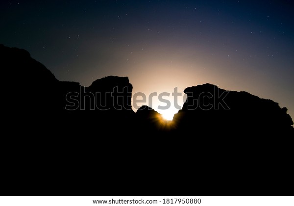 The rising of the moon between the rocks.\
Its\
light dazzles creating a halo of orange light in its path.\
The\
stars are in the sky watching her come out.\
Ideal for backgrounds,\
advertising, decoration