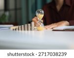 Rising stack of coins and running sand clock on the table. Growing of income, saving or return investment through time. Time and money concept.