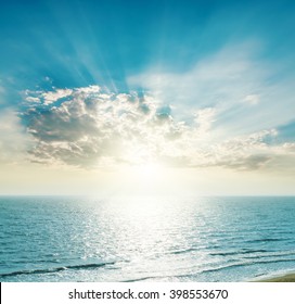 rising sun on the horizon, blue sea and clouds