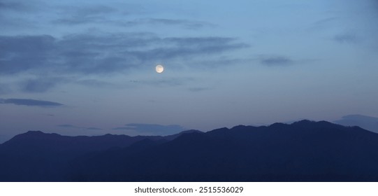 Rising yellow full moon over mountains. Super moon on cloudy blue sky heaven over night peak of mountain. evening scene.  - Powered by Shutterstock