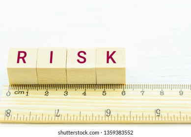 Risk Assessment / Risk Analysis And Fraud Management Concept : Letters RISK On Wood Square Cubes And A Ruler, Depicts Danger Of Risk That Victim Or Financial Investor Must Avoid And Not Involved In