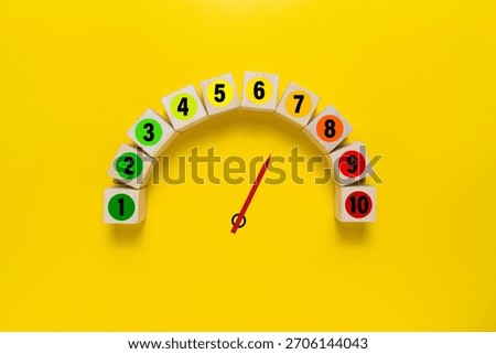 risk level meter indicator from low to high with 1 to 10 scale numbers on wooden blocks isolated on yellow background. concept of risk management
