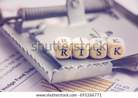 Risk management and risk tolerance concept : Dices are put in a word RISK on a rat trap, risk is a probability or threat of damage, liability, loss and may be avoided through preemptive action.