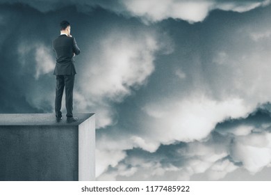 Risk And Research Concept. Young Businessman Looking Down From Rooftop. Sky Background 