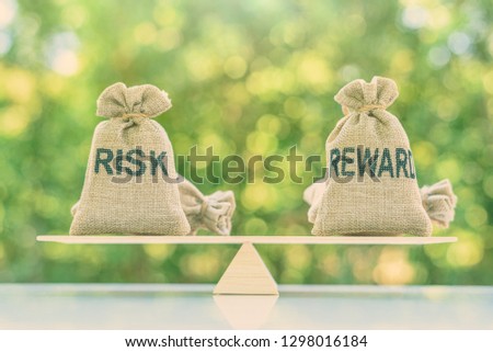 Risk reward ratio / risk management concept : Risk and reward bags on a basic balance scale in equal position, depicts investors use a risk reward ratio to compare the expected return of an investment