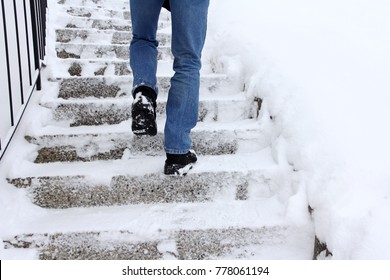 Risk Of Slipping When Climbing Stairs In Winter. A Man Goes Up A Snow-covered Staircase