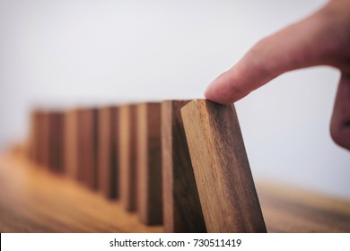 Risk and strategy in business, Close up of businessman hand gambling starting push wooden block on a line of domino Concept