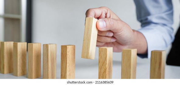 Risk and strategy in business, Close up of business woman hand gambling placing wooden block on a line of domino.