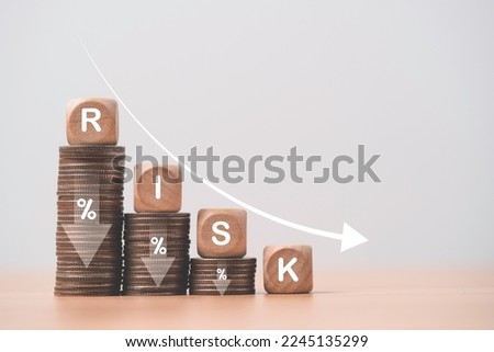 Risk wording on decreasing coins stacking with down arrow for financial banking risk analysis and management ,Low risk low return concept.