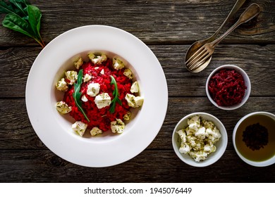 Risotto with beetroots and feta cheese on wooden table 