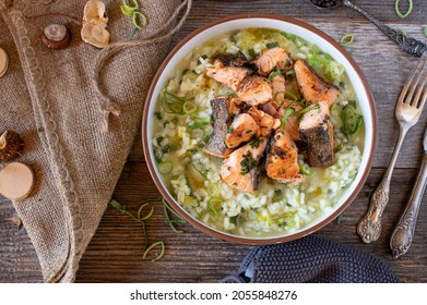 Risotto With Fresh Leek And Parmesan Cheese. Served With Pan-fried Salmon Fillet In A Rustic Bowl On Wooden Table. Homemade Fresh Cooked Meal. Overhead View