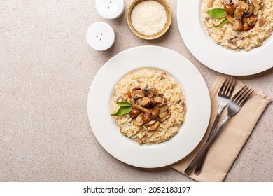Risotto with mix of mushroom and taleggio cheese on stone beige table. Two portions. Top view. Copy space.