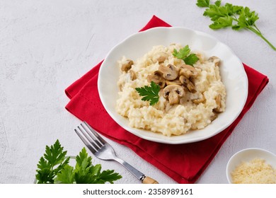 Risotto with mushrooms garnished with parsley in a light plate on a white concrete background. Risotto recipes. Italian Cuisine - Shutterstock ID 2358989161