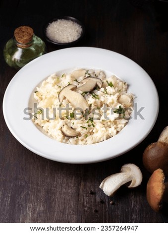 Risotto with mushrooms porcini (Boletus Edulis) on wooden dark rustic background. Healthy tradition nord Italian and French recipes, autumn and winter homemade cooking	