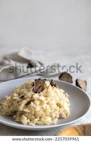 Risotto with wild porcini mushrooms and black truffles from Italy served in a plate close up on white table, copy space. Eating Italian gourmet cousine