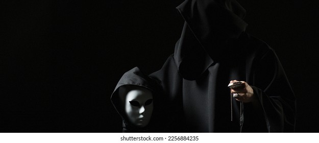 Rite of deal with devil. Sinner in black clothes and demon in sleeve. Man possessed by devil. Evil sorcerer talking with mask. Schizo speaks to himself. Cursed assassin in dark room. Vicious mage. - Shutterstock ID 2256884235