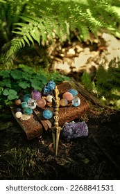 Ritual knife, set of minerals and magic witch book in forest, blurred natural green background. Phurba is three-sided knife, traditionally of Indo-Tibetan Buddhism for esoteric spiritual practice