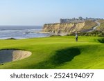 The Ritz Carlton Hotel at Half Moon Bay, California, glows in the soft light of a Pacific sunset. This luxurious landmark, set against the coastal landscape, showcases the serene beauty of the area.