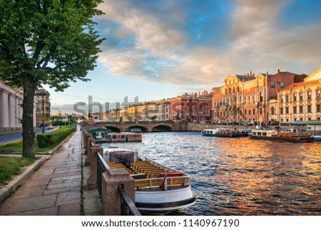 River boat trips on the Fontanka River in St. Petersburg on a summer sunny evening and Anichkov Bridge in the distance