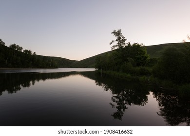 River by the hills with water reflection and clear sky at dusk