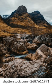 The River Coe flows through Glen Coe with The Three Sisters mountains in early spring, Scotland