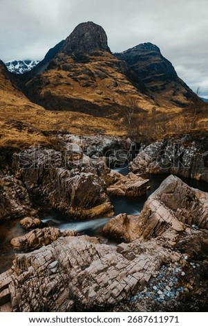 The River Coe flows through Glen Coe with The Three Sisters mountains in early spring, Scotland