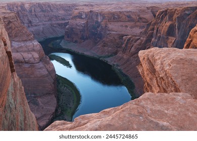 A river cuts through a deep canyon, its waters flowing swiftly between massive rocks that tower overhead. The canyon walls are rugged and imposing, casting shadows on the water below.