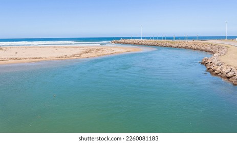 River estuary mouth water flowing out into blue ocean sea  along beach coastline on a summer day. - Shutterstock ID 2260081183