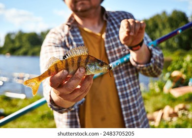 river fish in hand on a caught hook close-up on the background of water - Powered by Shutterstock