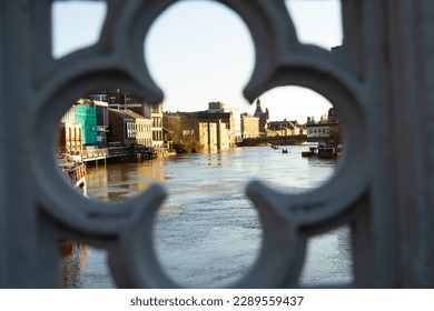 A river in flood viewed through a pattern in a bridge over the river 