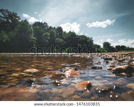 River flowing through the rocks under the clear sky .