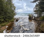 A river flows through a pine tree forest and into beautiful Lake Superior, Great Lakes, Upper Peninsula, Michigan 