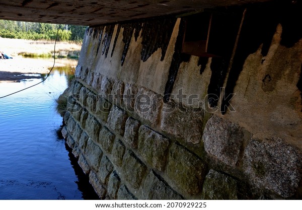 a river flows\
under the bridge. asphalt flows out of the bridge, which melts with\
heat in the summer. it flows slowly along the wall and when it\
cools it remains motionless.