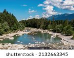 River Gail flowing through the Schuett in the natural park Dobratsch in Villach, Carinthia, Austria. Gailtaler and Villacher Alps. Riverbank is full of massive rocks. View on Dreilaendereck